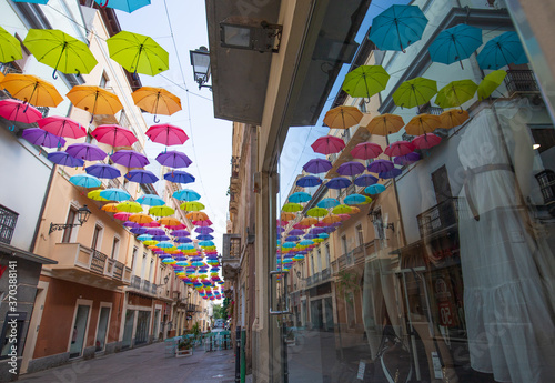 Iglesias, Italy: Colorful umbrellas hanging over a street in old Iglesias city in a sunny day 