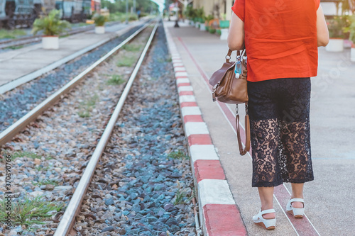 Mini portable alcohol gel bottle to kill Corona Virus(Covid-19) hang on leather shoulder bag of woman at railway staion. New normal lifestyle. Health care concept. Selective focus on alcohol gel