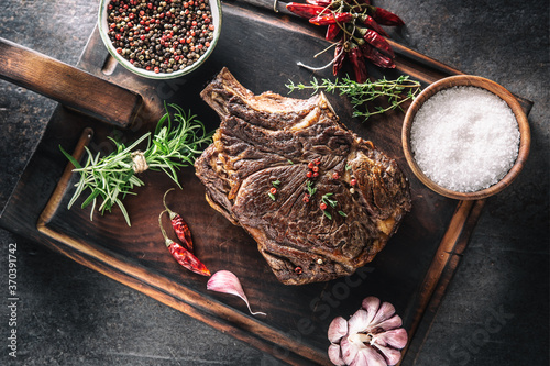 Quadro em tela Grilled beef steak with spices herbs salt pepper and garlic on wooden cutting bo