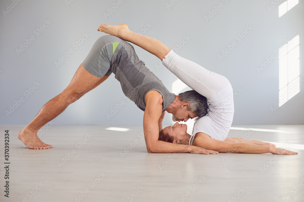 Naklejka premium Couple yoga pose on the floor in a studio class.