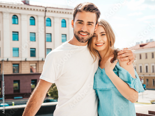 Portrait of smiling beautiful woman and her handsome boyfriend. Woman in casual summer jeans dress. Happy cheerful family. Female having fun. Couple posing on the street background