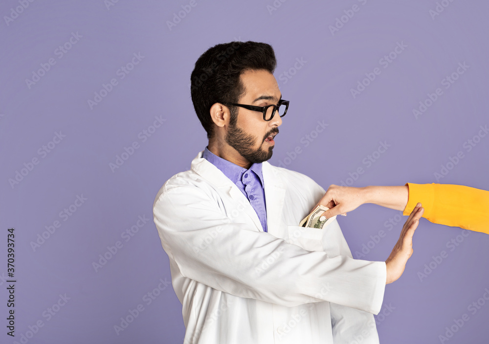 Stop corruption. Shocked Indian doctor saying no to bribe from female patient on violet background Stop corruption. Shocked Indian doctor saying no to bribe from female patient on violet background