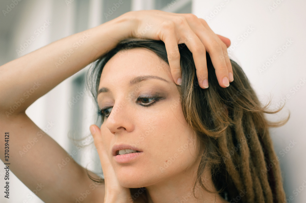 Fototapeta premium Indoors female portrait of a woman with dreadlocks hairstyle and smoky eyes makeup