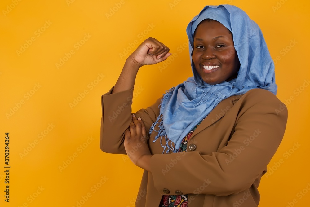 Portrait of beautiful Caucasian woman isolated over yellow background, showing muscles after workout. Health and strength concept. Portrait of beautiful Caucasian woman isolated over yellow background, showing muscles after workout. Health and strength concept.