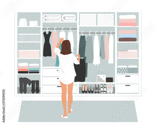 Wardrobe storage room and young elegant woman in front of open closet full of elegant dresses. Everyday choice what to wear into the office