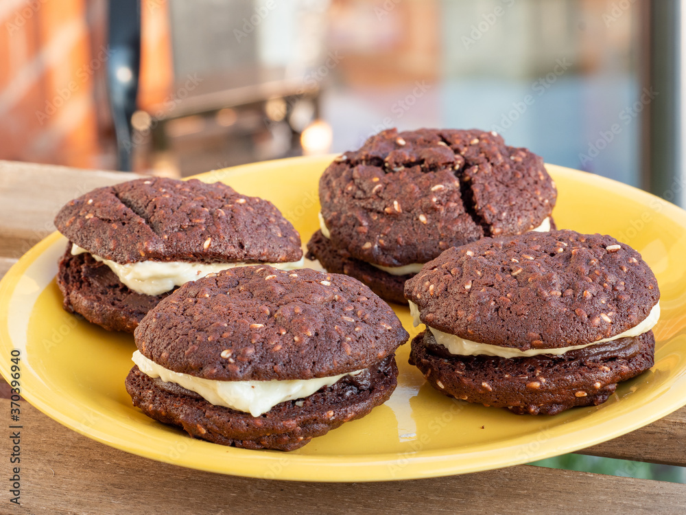 Chocolate and sesame yo-yo's chocolate biscuits or cookies on a yellow plate outdoors Chocolate and sesame yo-yo's chocolate biscuits or cookies on a yellow plate outdoors