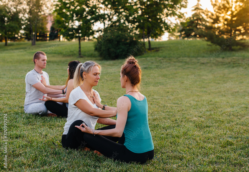 A group of people perform paired yoga exercises in a Park during sunset. Healthy lifestyle, meditation and Wellness A group of people perform paired yoga exercises in a Park during sunset. Healthy lifestyle, meditation and Wellness