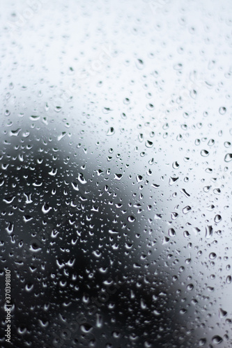 Raindrops dripping on glass out of focus with blurred background