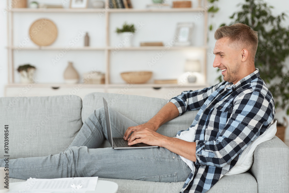Happy man chatting online on laptop with friend at home