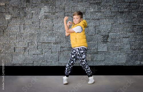 Playful kid has fun while dancing against the wall.