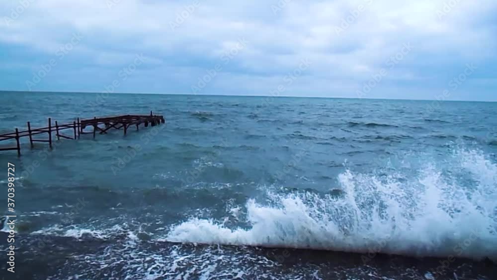 Sea storm, waves crashing against the pier. Splashes on the dock, foam on the waves. Cloudy day and bad weather at sea. HD video