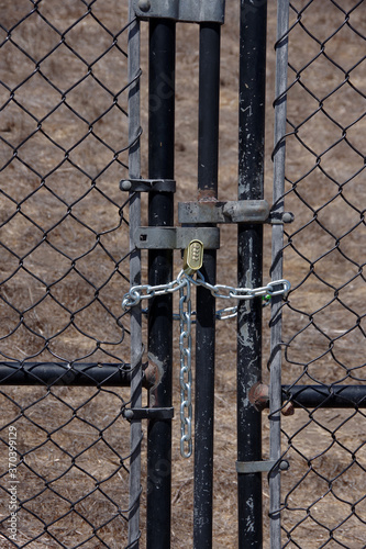 Close-up view of a chainlink fence and gate locked with a heavy chain and a number padlock