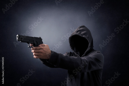 Hooded man with a gun in the dark