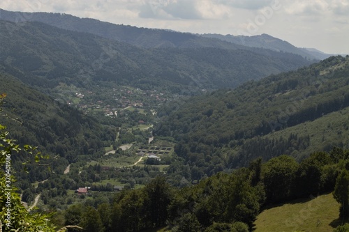 Beautiful Village on Carpathian Mountain with River, Forest, Buildings on sunny Day © Eugen