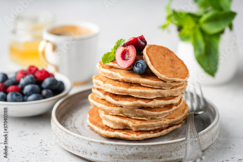 Healthy oat pancakes with berries on a craft ceramic plate. Vegan breakfast food