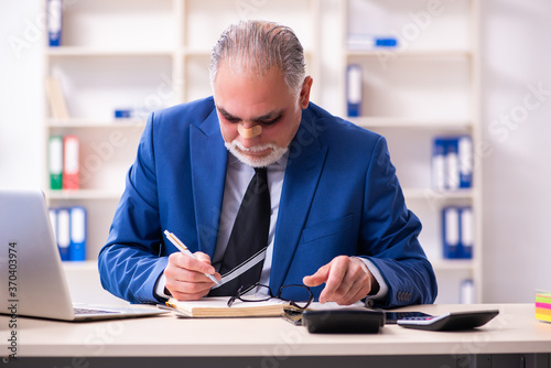 Old face injured employee sitting in the office