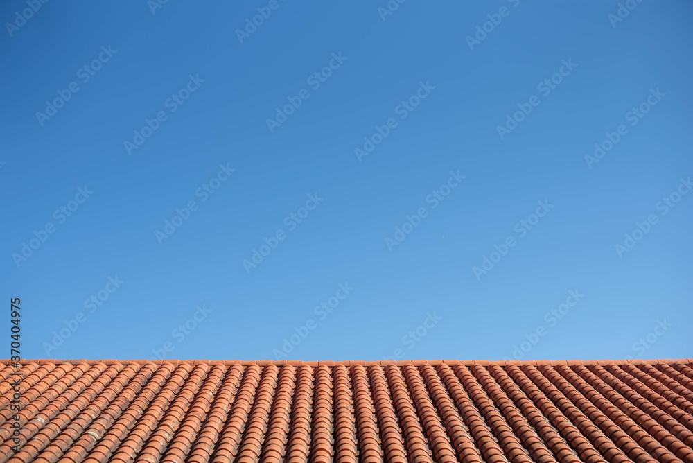 cielo azul sobre tejado de tejas rojas