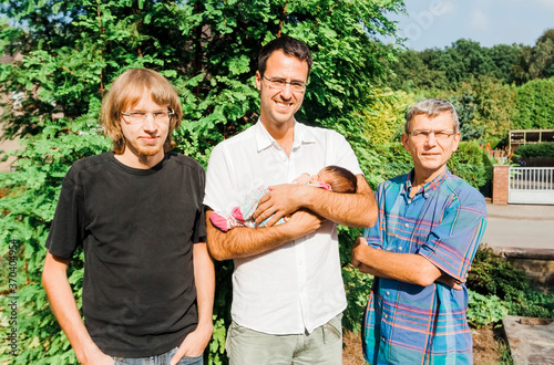 Happy men of multi-generational family with newborn baby outdoors