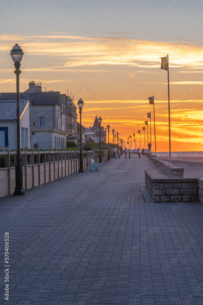 Langrune Sur Mer, France - 08 03 2020: people walking on the pier and watching the sunset