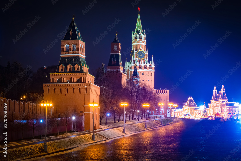 Evening Moscow. Towers of the Moscow Kremlin against the dark sky. Spasskaya tower of the Kremlin with chimes. The building of the Historical Museum is decorated with garlands. Red square in Moscow.