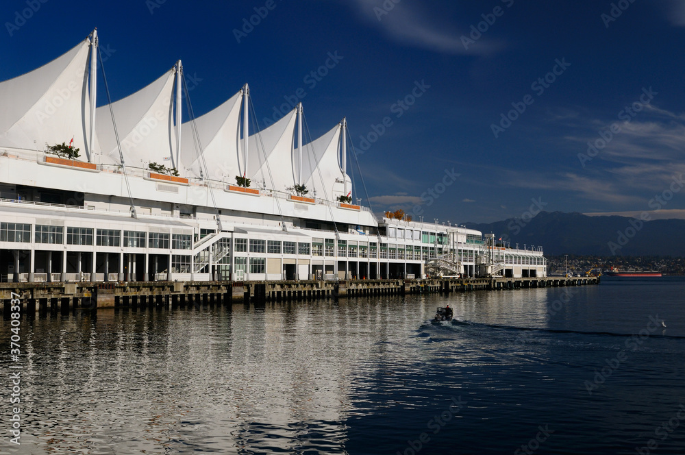 Canada Place pier and sails with North Vancouver Coastal mountains and cargo ship