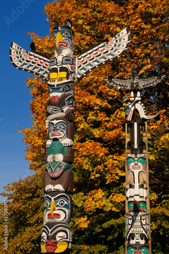 фотографія Kakasolas and Chief Wakas totem poles in Stanley Park Vancouver with orange mapl