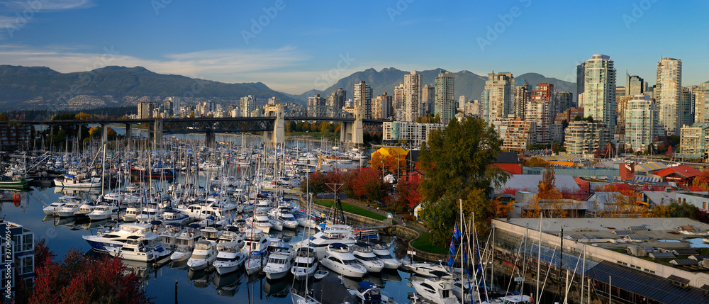 Panorama of boats moored at Granville Island Boat Yard and Burrard bridge and Coastal mountains Vancouver