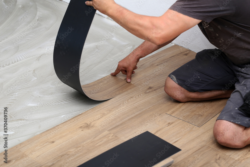 The worker installing new vinyl tile floor - obrazy, fototapety, plakaty 