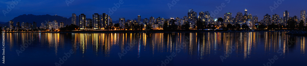 Wide Panorama of West End Vancouver skyline at dusk reflected in English Bay with Grouse Mountain