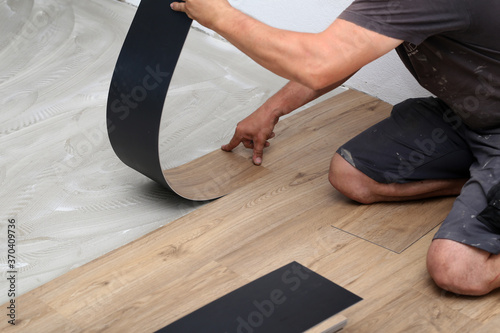 The worker installing new vinyl tile floor photo