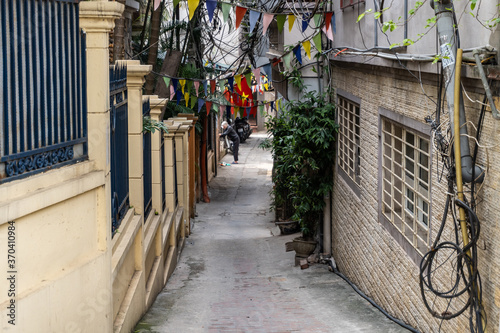 Fototapeta Naklejka Na Ścianę i Meble -  Narrow Hanoi lane and an elderly vietnamese woman