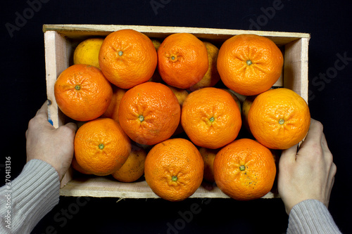Cajon de mandarina cultivador fondo negro manos hombre