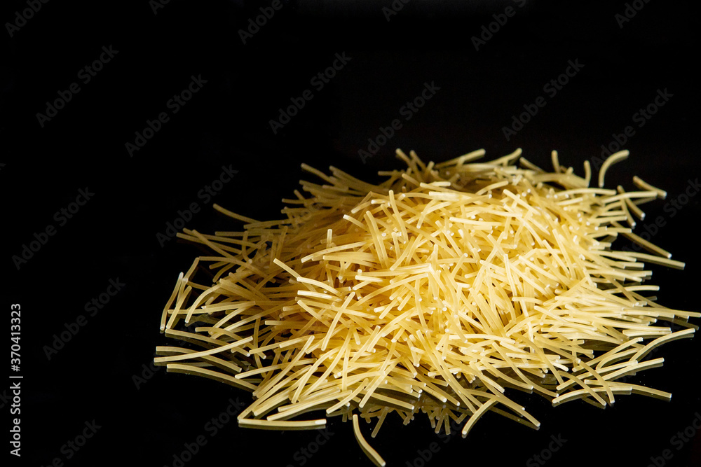 Dry spaghetti stands on a black background. Cooking concept. Space for text.