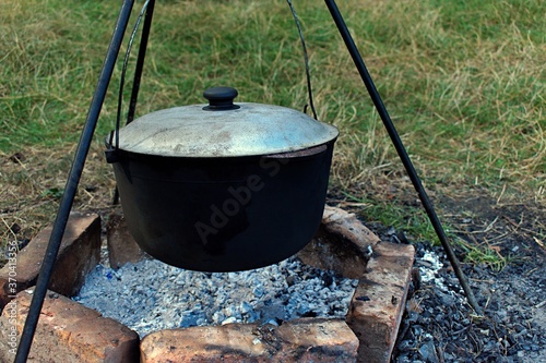 outdoors cooking pilaf in a cauldron on hot coals