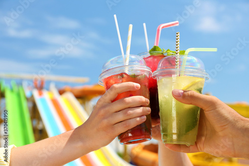 People with refreshing drinks in water park, closeup