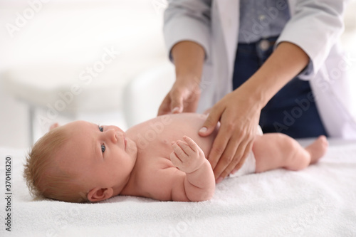 Doctor examining cute baby indoors, closeup. Health care