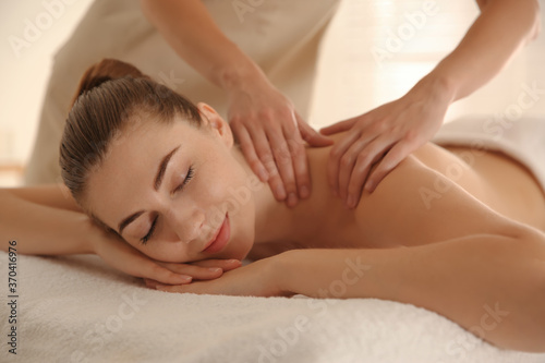 Young woman receiving shoulder massage in spa salon
