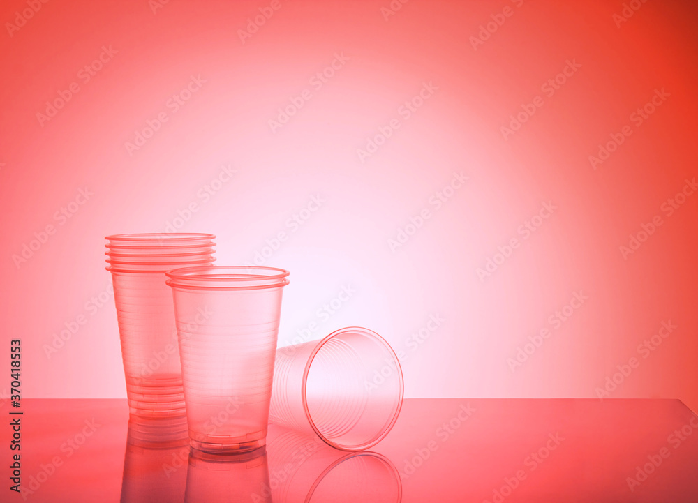 empty disposable plastic cups on a red background with copy space - obrazy, fototapety, plakaty 
