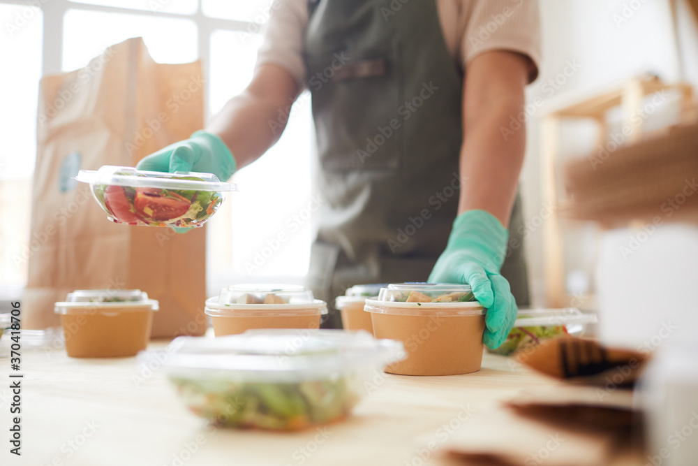 Close up of unrecognizable female worker wearing protective gloves while packaging orders at food delivery service, copy space Close up of unrecognizable female worker wearing protective gloves while packaging orders at food delivery service, copy space