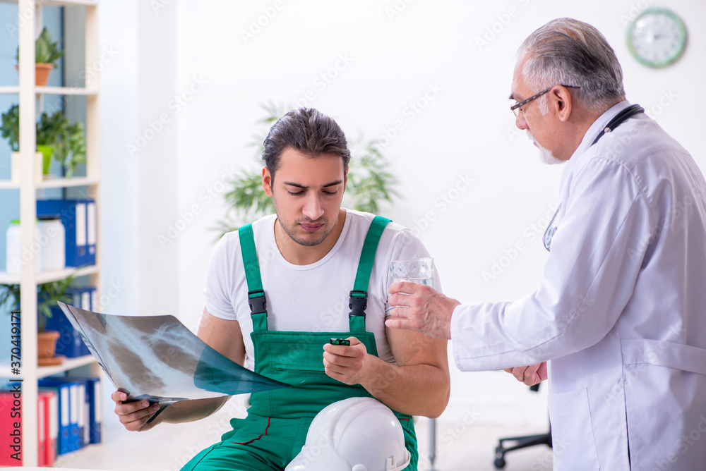 Fototapeta premium Young male contractor visiting old doctor