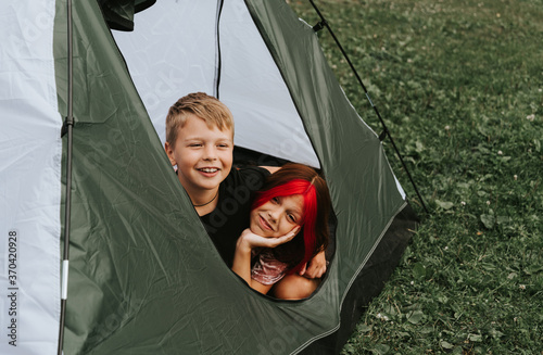 children boy and girl in camping tent on the river bank in a picturesque landscape