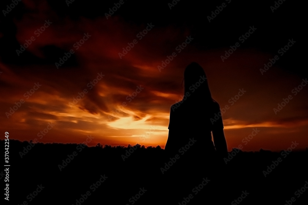 Silhouette of a girl on a background of dramatic sunset.