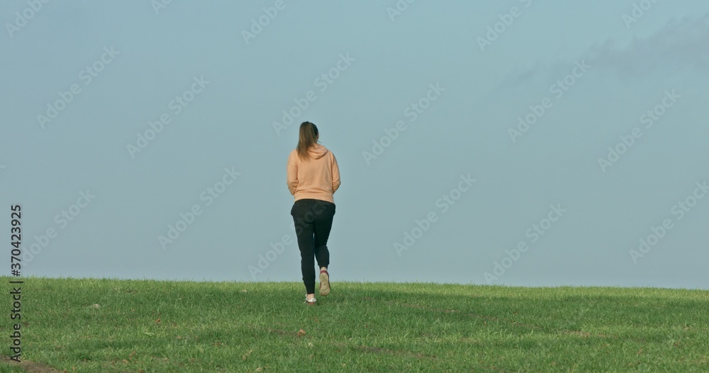 Woman running on spring green grass.