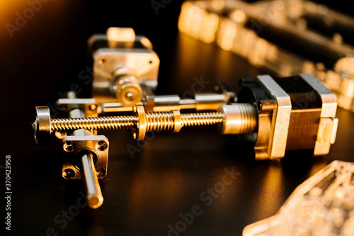 motor and guides for the laser machine. details of the engraving machine, black warm background, orange light. photo