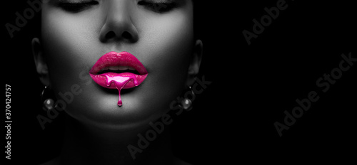 Purple Paint dripping, lipgloss drops on sexy lips, bright liquid paint on beautiful model girl's mouth. Lipstick. Make-up. Beauty face makeup, close up. Isolated on black background © Subbotina Anna