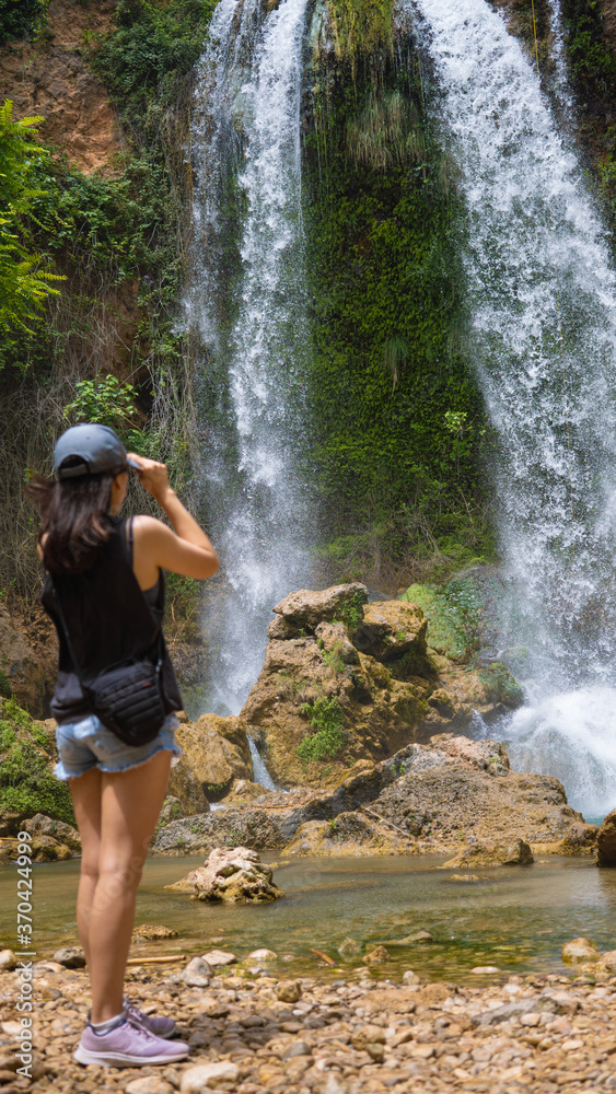 Mujer joven tomando una foto de una cascada increíble