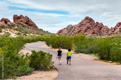 Two women walk the trail towards the sandstone buttes of Papago Park in Phoenix, Arizona.
