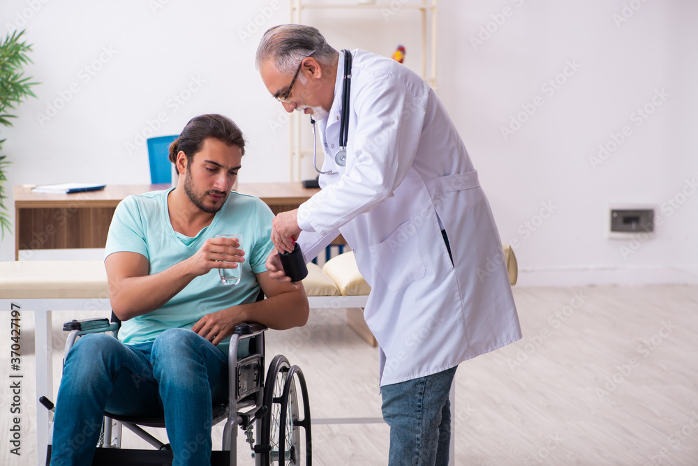 Experienced doctor and young male patient in wheel-chair Experienced doctor and young male patient in wheel-chair