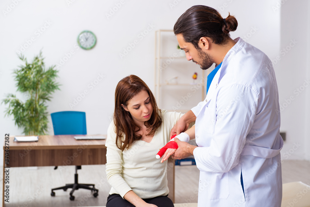 Fototapeta premium Young hand injured woman visiting male doctor traumatologist