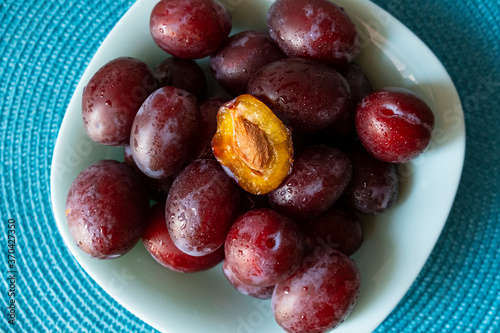 red plums on a plate. half a broken plum.